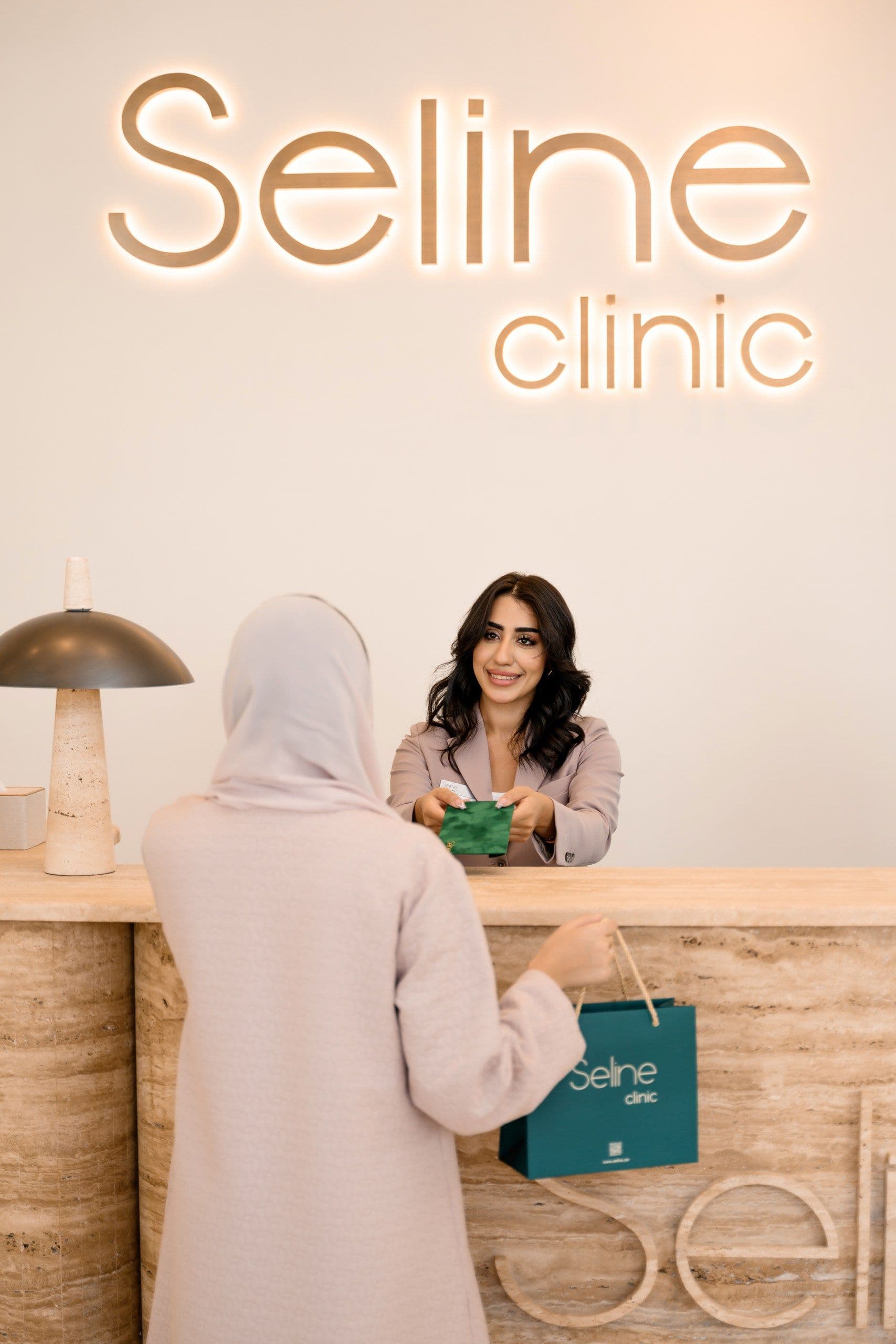 Receptionist welcoming a client at the front desk of Seline Clinic